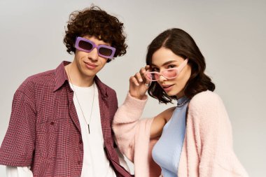 Genç bir çift şık kıyafetler ve aksesuarlarla poz verirken cazibe ve romantizm sergiliyor..