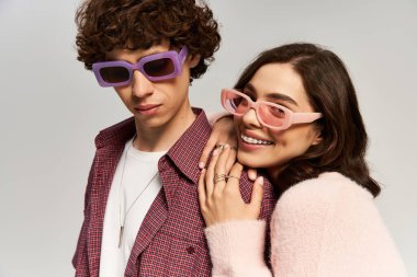 Şık bir erkek ve kadın kucaklaşır, sevgi ve neşe saçar, moda kıyafetlerini sergilerler..