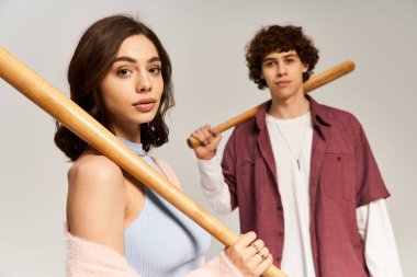 Şık bir çift bir arada duruyor, her biri bir beyzbol sopası tutuyor, bağlarını gösteriyor..