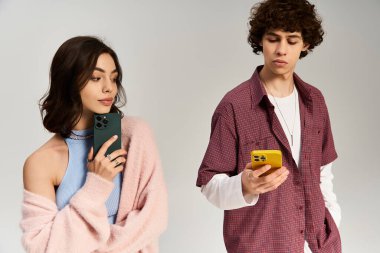 Genç çift, birbirlerine şakacı bakışlar atarak ve telefonlarını kullanarak aşklarını ve tarzlarını ifade ederler..