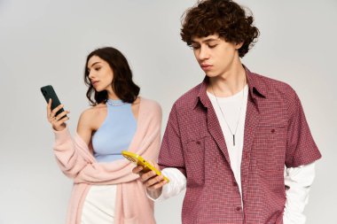 Moda ileri görüşlü bir çift, telefonlarına dalmış, modern romantizmi somutlaştıran bir anı paylaşır..