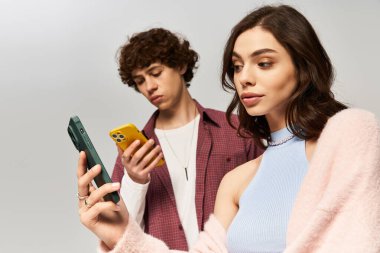 Tarz sahibi genç bir çift, gülümseyerek akıllı telefonlarıyla eğlenmeyi sever..