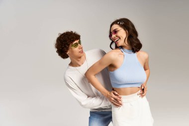 Genç bir çift, neşe saçan, modaya uygun kıyafetlerle poz verirken sevgilerini sergiliyor..