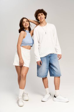 Neşeli genç bir çift birbirine yakın duruyor, neşeli bir pozda aşk ve tarz yayıyorlar..