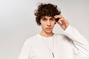 Yakışıklı, kıvırcık saçlı, şık giyinmiş, sakin, beyaz arka planda..