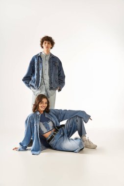 Moda çifti, şık kot kıyafetleri içinde birlikte poz verirken sevgi ve güven yayıyor..