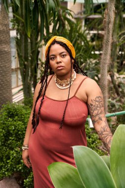 Zarif bir Afrikalı Amerikalı kadın serada gelişen bitkilerin arasında poz veriyor..