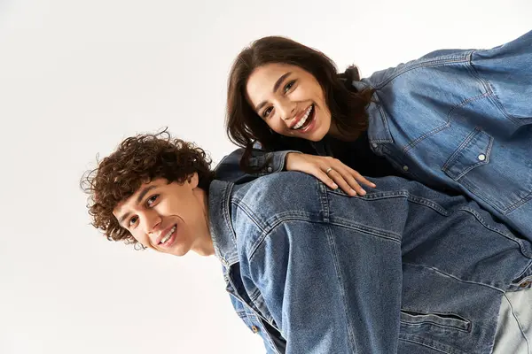 Neşeli genç çift, modaya uygun kot kıyafetlerle kahkahalar ve şakalaşmalar paylaşıyor..