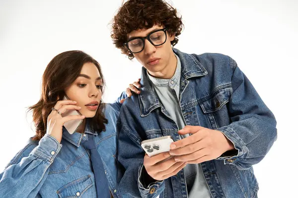 Genç bir çift sohbet ediyor ve akıllı telefon kullanıyor. İkisi de şık görünüyor ve birbirlerinden hoşlanıyorlar..