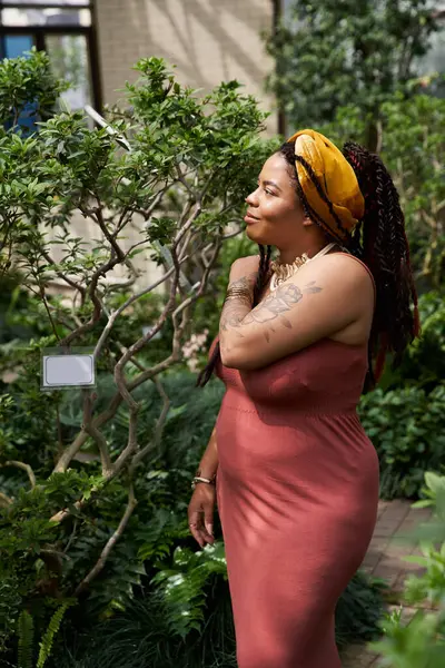 Süslü örgü ören afro-amerikalı bir kadın bitkilerden oluşan serada keyif alıyor..