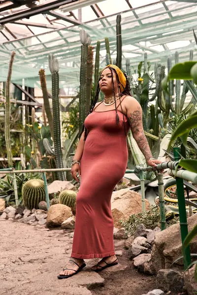 Zarif bir Afrikalı Amerikalı kadın gelişen bitkilerin arasında zarif bir şekilde duruyor, neşe saçıyor..