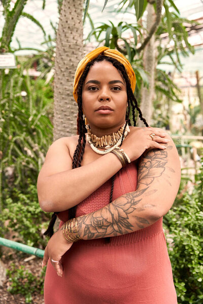 A joyful african american woman with braids embraces nature, surrounded by lush greenery.