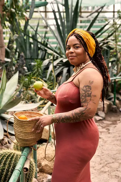 Saçları örgülü neşeli bir kadın yemyeşil bir serada huzurlu bir anın tadını çıkarıyor.