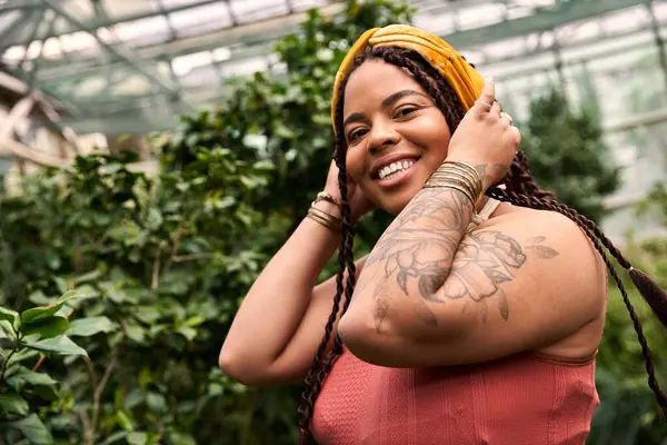Neşeli bir Afrikalı Amerikalı kadın yemyeşil bir seranın güzelliğinin tadını çıkarıyor..
