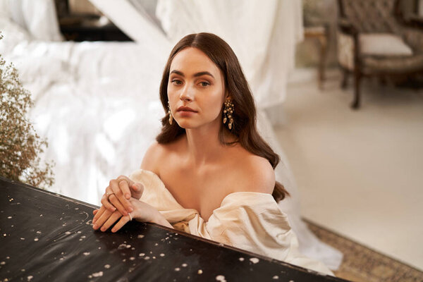 A stunning young woman poses elegantly with a serene expression against a vintage backdrop.