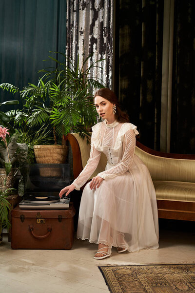 Красивая женщина сидит изящно, в винтажном платье, в окружении растений и классического декора.