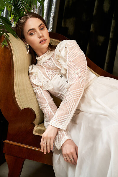 Молодая женщина, украшенная в деликатном винтажном платье салоны изящно, источая элегантность и красоту.