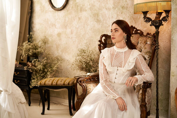 A young woman in a vintage dress sits gracefully among decor, showcasing elegance and charm.