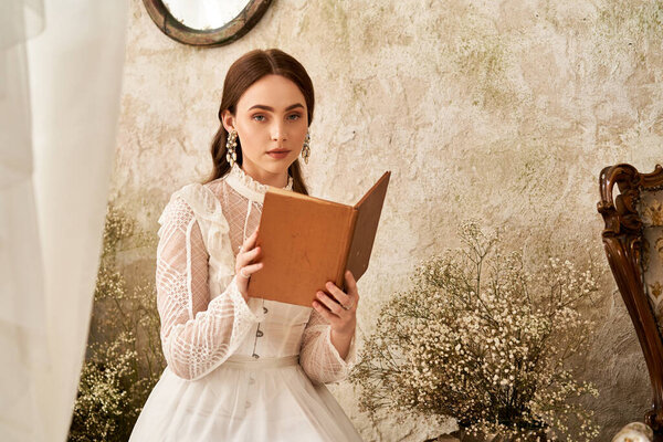 Сложная женщина в красивом винтажном белом платье читает тихо, в окружении успокаивающего декора.