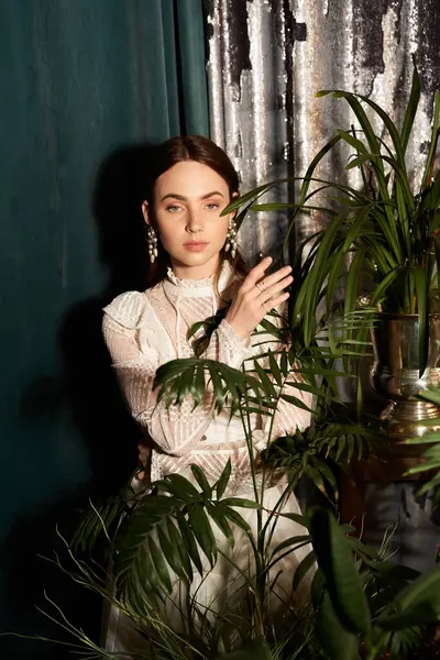 Kaliteli elbiseli çekici genç bir kadın büyüleyici bir ortamda bitkilerle nazikçe etkileşime girer..