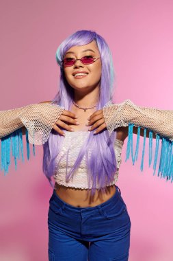 Lavanta gibi saçları olan şık bir kadın hayat dolu bir ortamda parlıyor, eşsiz modasını sergiliyor..