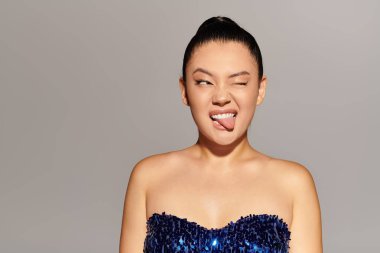 Güzel, modaya uygun bir kadın neşeli yanını gösteriyor, göz kırpıyor ve dilini dışarı çıkarıyor..