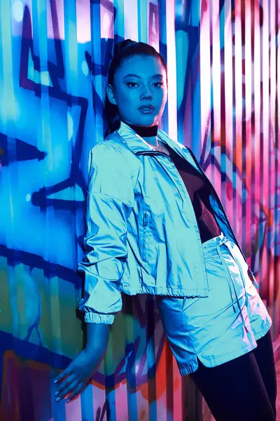 Güzel bir kadın duruşu ve rengarenk grafitilerin yanında duruyor..