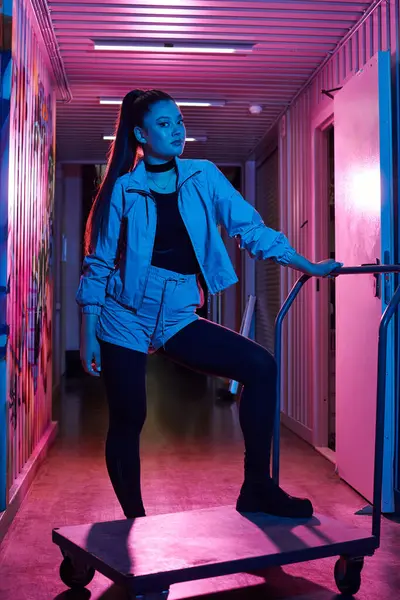 Çekici bir kadın eşsiz tarzını renkli bir koridorda sergiliyor, zarif bir poz veriyor..