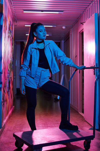 Потрясающая женщина демонстрирует свой уникальный стиль в красочном коридоре, поражая элегантной позой.