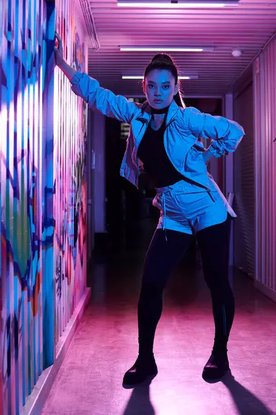 Kendine güvenen bir kadın, neon ışıklı bir koridorda gece poz verir..