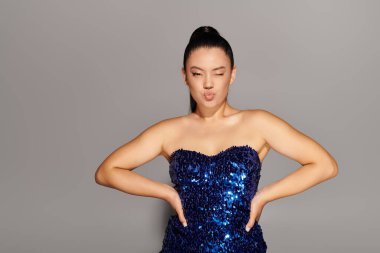 Güzel bir kadın kendine güveni ve çekiciliğiyle neşeyle poz veren şık görünümünü sergiliyor..