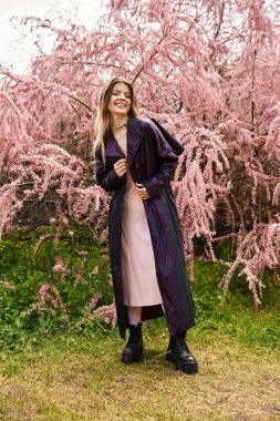 Pembe Tamarix 'den gülümseyen, çekici, ceketli bir kadın..