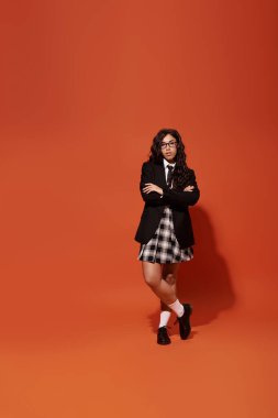 Kendine güvenen bir kadın kollarını kavuşturup şık öğrenci stilini ve enerjik enerjisini sergiliyor..