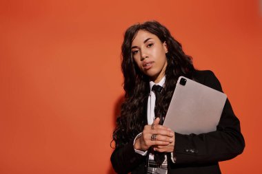 Güzel bir kadın kendine güvenerek ayakta duruyor, elinde bir tablet, şık bir öğrenci havası sergiliyor..