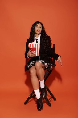 Genç bir kadın elinde patlamış mısırla bir yönetmen koltuğunda oturuyor..
