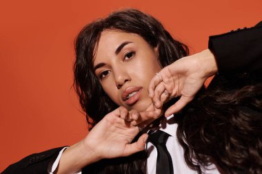 Gömlekli ve kravatlı güzel bir kadın elleriyle poz veriyor, estetik bir havayı vurguluyor..