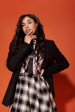 Güzel genç öğrenci kendine güvenerek poz veriyor. Şık kıyafetler, ekose etek ve spor ceket..