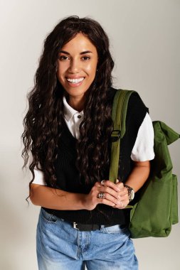 # Genç bir kadın gururla ışıldıyor, gururla gösteriyor öğrenci havasını ve yeşil sırt çantasını #.