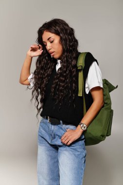 Güzel öğrenci, içeride rahat bir duruşu ve modaya uygun kıyafetleri olan genç estetikleri sergiliyor.