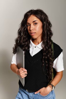 Kendine güvenen genç bir kadın dizüstü bilgisayar tutuyor çağdaş öğrenci estetiğini özgüvenli bir anda somutlaştırıyor..