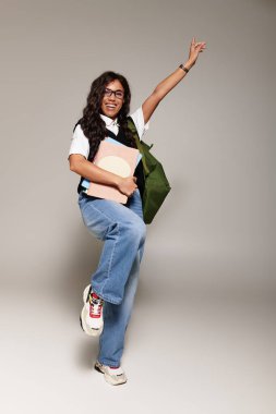 Güzel, genç bir öğrenci, neşeli bir poz veriyor. Günlük kıyafetle, canlı bir enerji yayıyor..