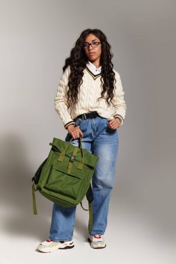 Modaya uygun genç bir öğrenci yumuşak ışıklandırmalı şık kıyafetiyle sergilenen bir estetik sunar..