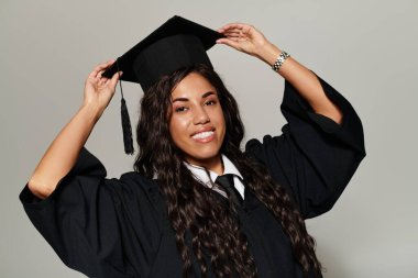 Genç bir kadın mezuniyet şapkasını çarpıcı bir elbiseyle ayarlıyor..