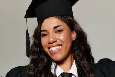 Güzel genç bir kadın mezuniyet kepi ve cübbesi giyer, mutluluk ve başarıyı ifade eder..