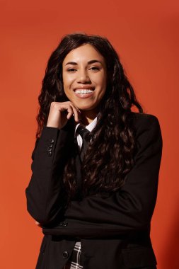 Kendine güveni tam bir kadın, turuncu bir zemine karşı güzelliğini sergiliyor..