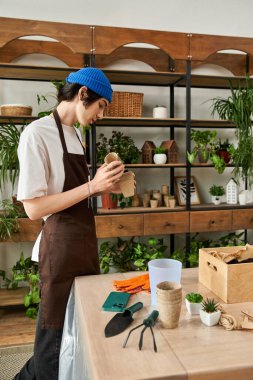 Mavi bereli genç bir adam parlak bir stüdyoda bitki nakletmeye odaklanmış..