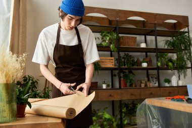 Samimi bir stüdyoda genç bir adam yemyeşil alanda bitki nakletmeye hazırlanıyor..