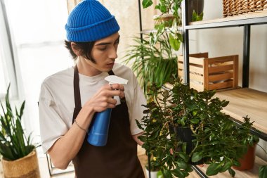 Genç ve çekici bir adam bitkileriyle canlı bir stüdyoda ilgilenir. Büyüme ve bakım sağlar..