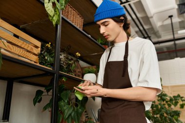Mavi bereli genç adam, parlak bir stüdyo ortamında verimli yeşillikler naklediyor..