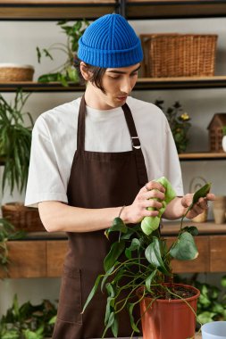 Genç adam, stüdyosunda yaratıcı bir anın tadını çıkarırken bitkilere özenle bakıyor..